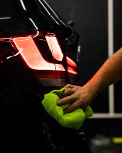 selective focus shot of man cleaning car s back headlight with microfiber cloth 1